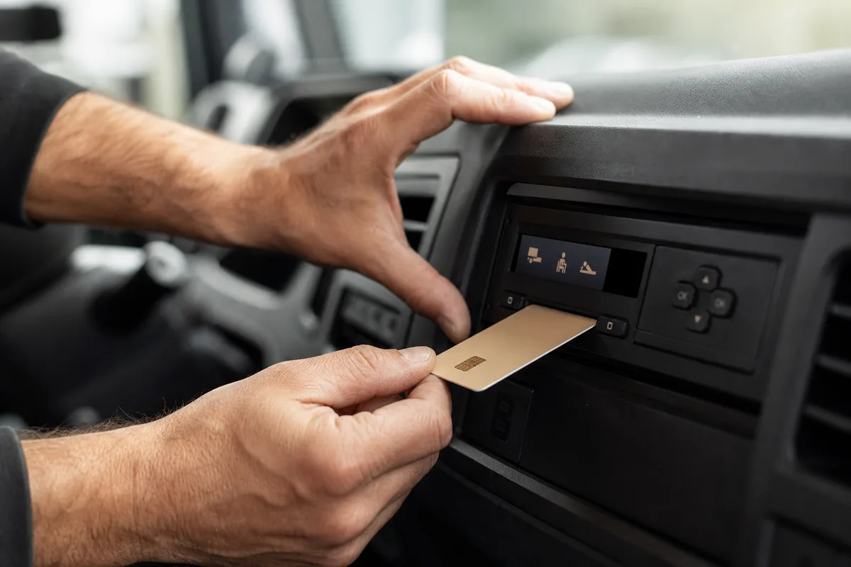 Mains d’un conducteur insérant une carte à puce dans le tachygraphe d’une cabine de poids lourd